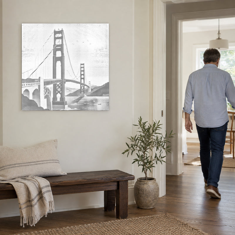 Punktmalerei-Leinwand “Golden Gate Bridge”, an einer hellen Wand, während eine Person durch die Tür geht.